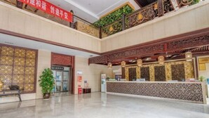 A spacious lobby with a reception desk, decorative panels, and a green plant. - Bianchui Hotel (Yingjiang)