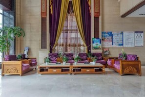 A lobby with seating arrangements, a reception desk, and informational posters on the wall. - Bianchui Hotel (Yingjiang)