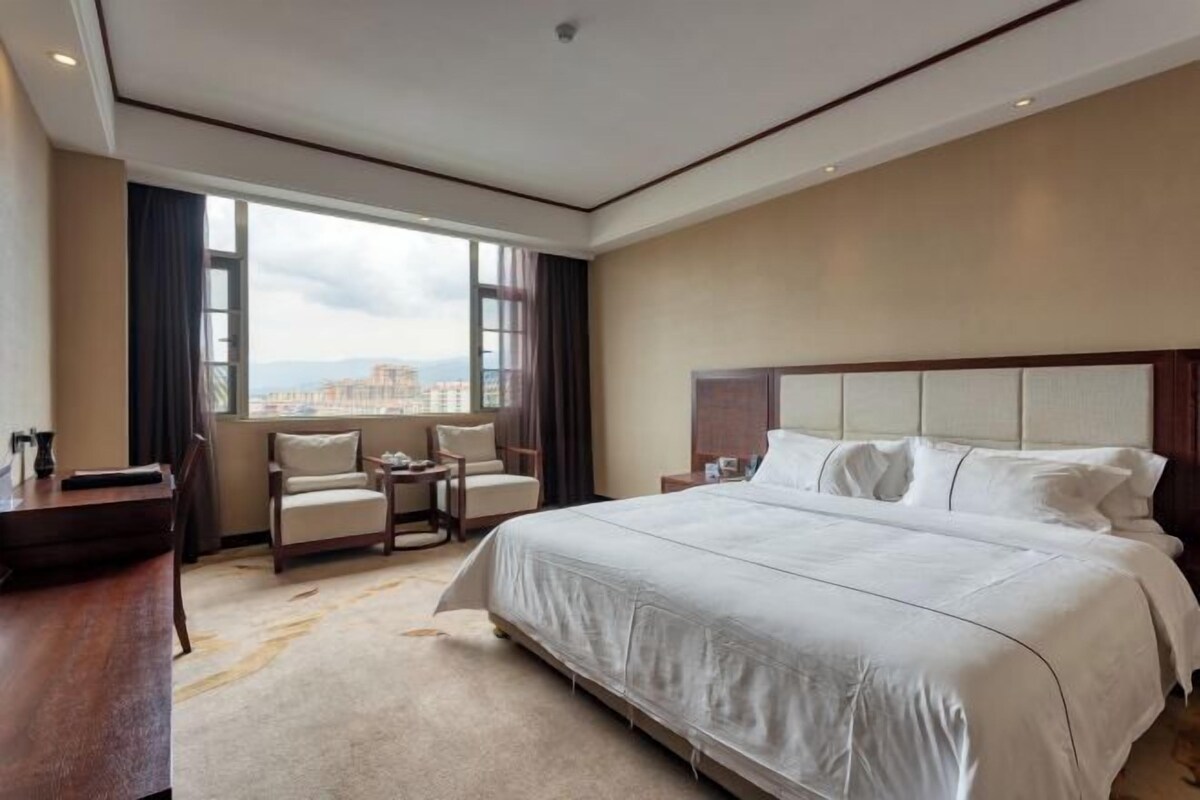 Une chambre d’hôtel avec un grand lit, un bureau, une chaise et une vue sur la ville.