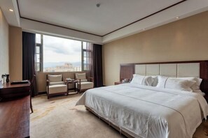 Une chambre d’hôtel avec un grand lit, un bureau, une chaise et une vue sur la ville.