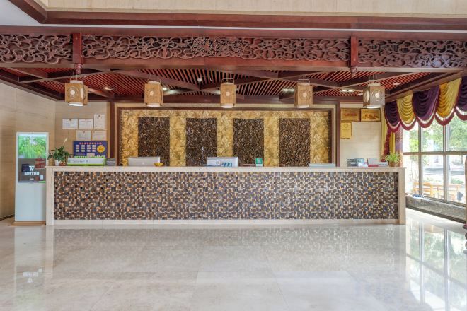 A reception area with a reception desk, a digital screen, and a decorative ceiling.