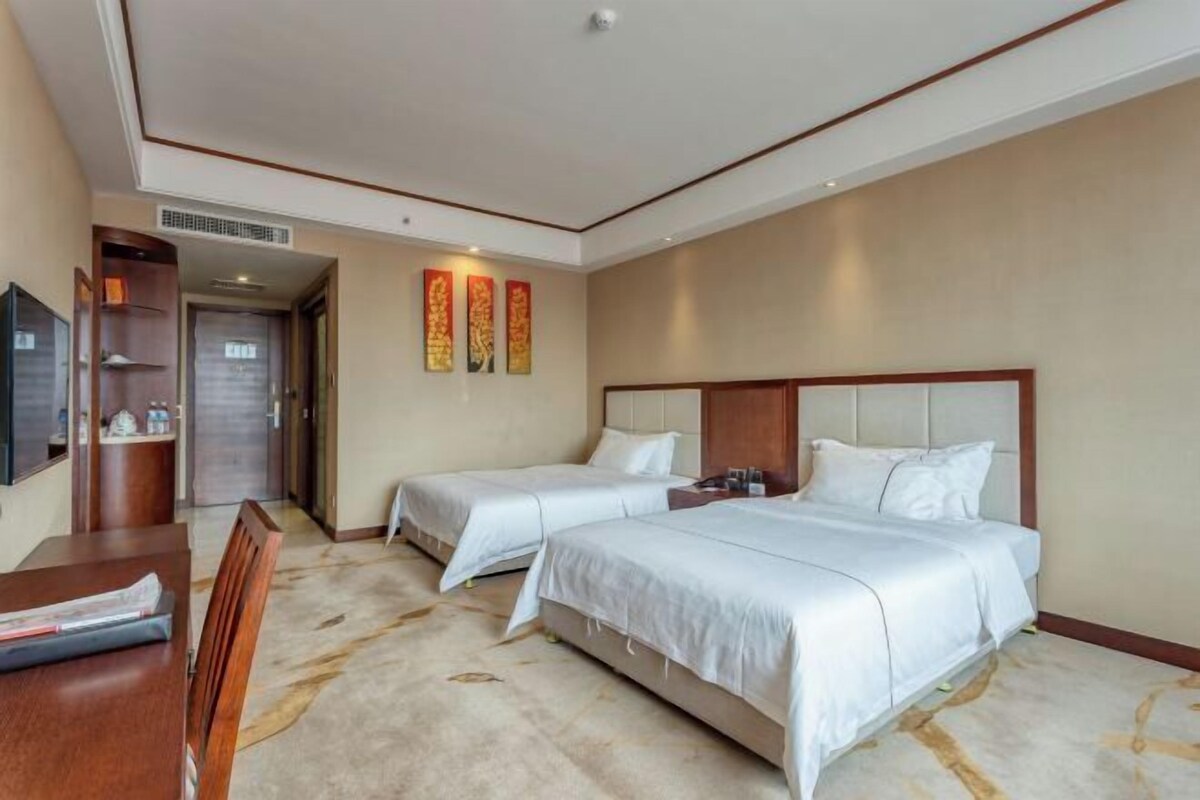 Une chambre d’hôtel avec deux lits, un bureau et une télévision.