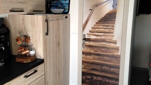 Een keuken met houten kastjes, een koffieapparaat en een televisie aan de muur.