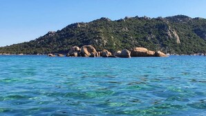 A coastal landscape with clear blue waters and a rocky island with dense vegetation. - Charming studio 300 m from the beach of Santa Giulia (Porto-Vecchio)