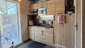Een moderne keuken met houten kastjes, een magnetron en een eethoek met een tafel en stoelen.