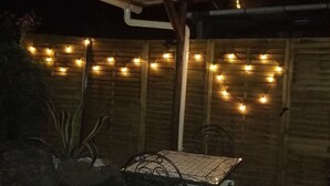 An outdoor patio area with a table and chairs, string lights, and a brick wall. - Charming studio 300 m from the beach of Santa Giulia (Porto-Vecchio)