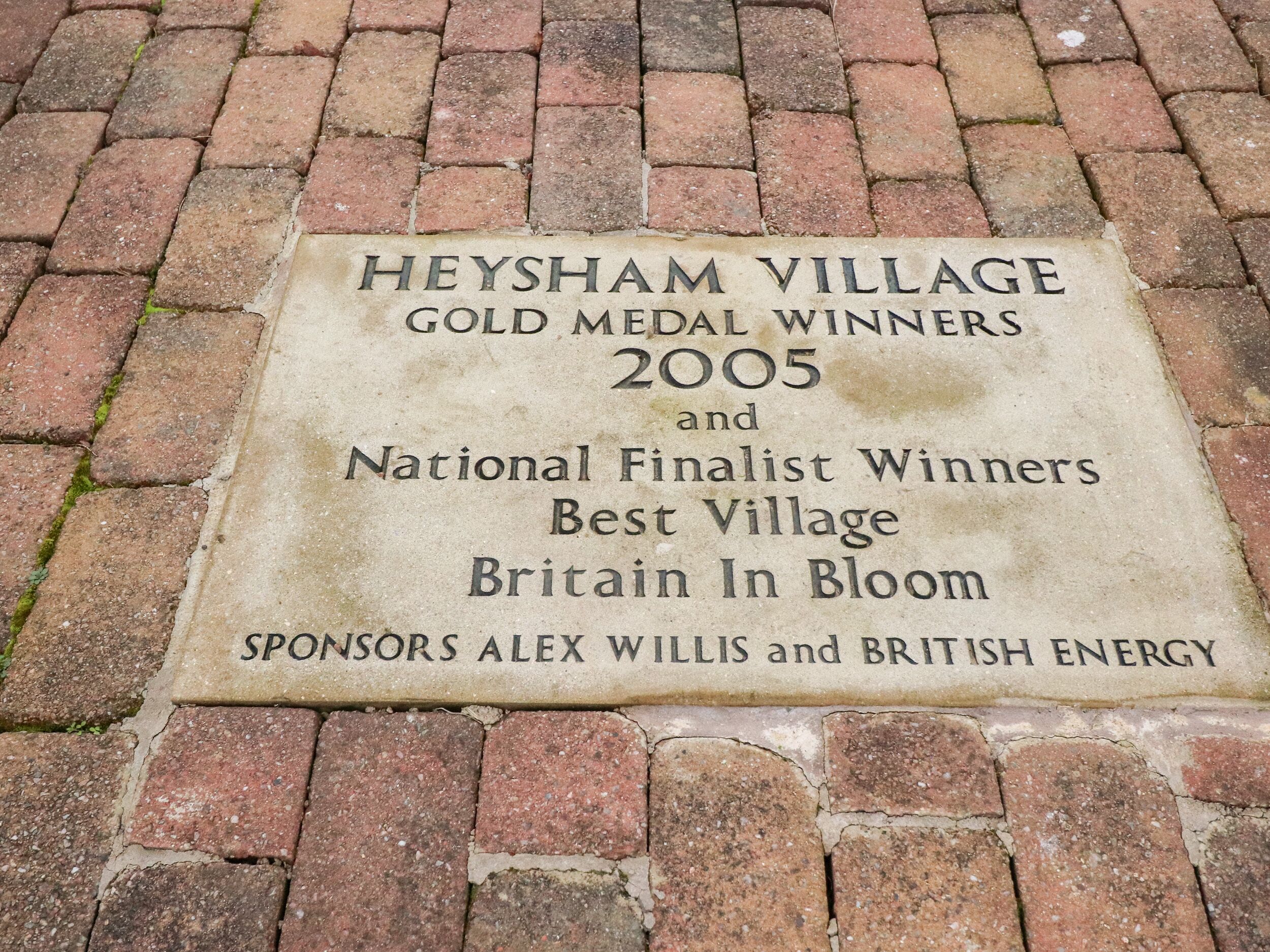 A plaque on a brick pavement.