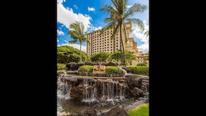 A hotel with a large building, a waterfall, and palm trees. - Hale Kai Pampered Ko Olina Villa (Kapolei)