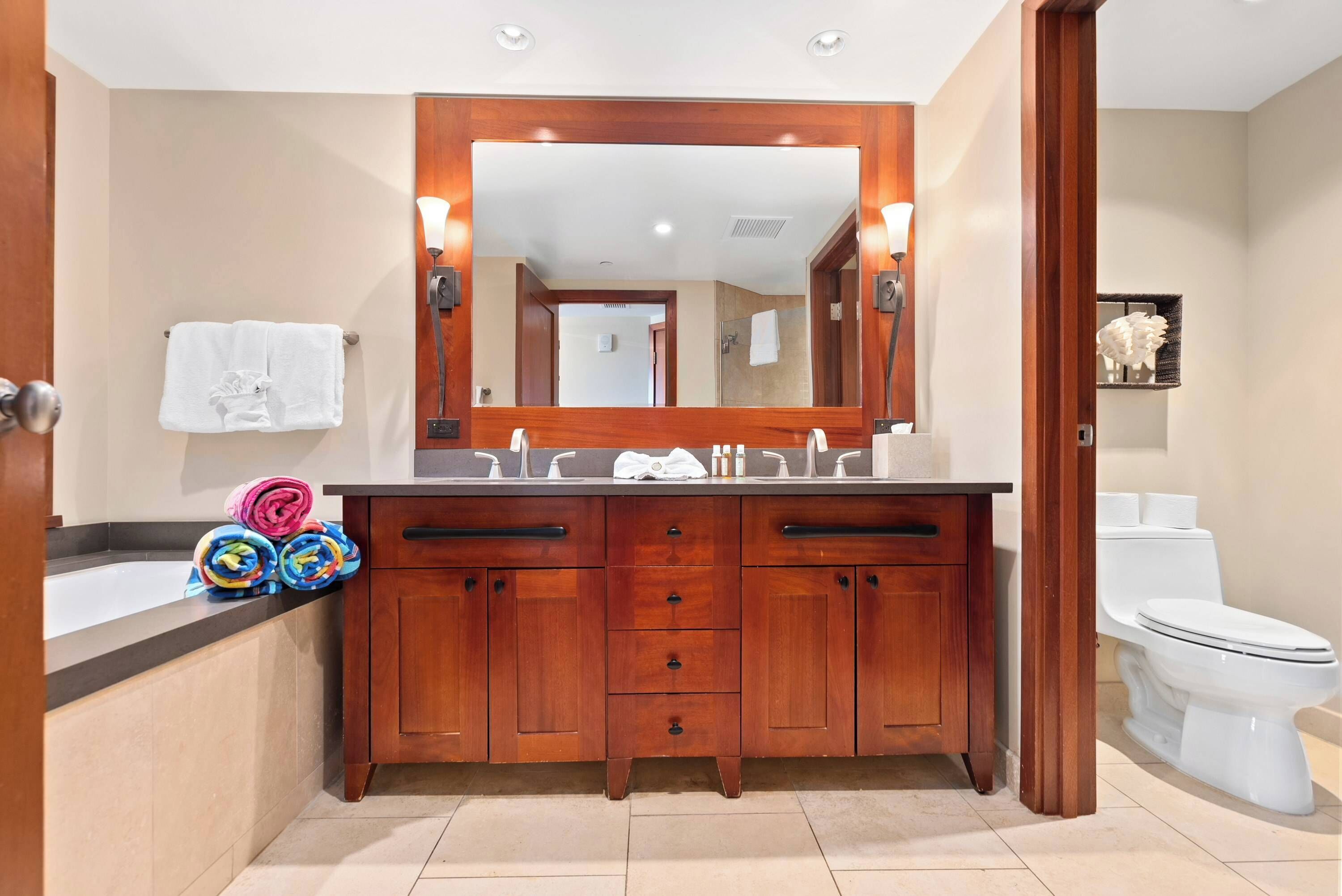 A bathroom with a wooden vanity, a large mirror, and a white toilet.