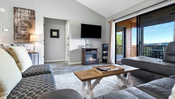 Una sala de estar moderna con chimenea, un ventanal grande y un televisor de pantalla plana.
