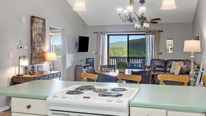 Una cocina con estufa, una mesa de comedor, sillas y vistas al exterior.