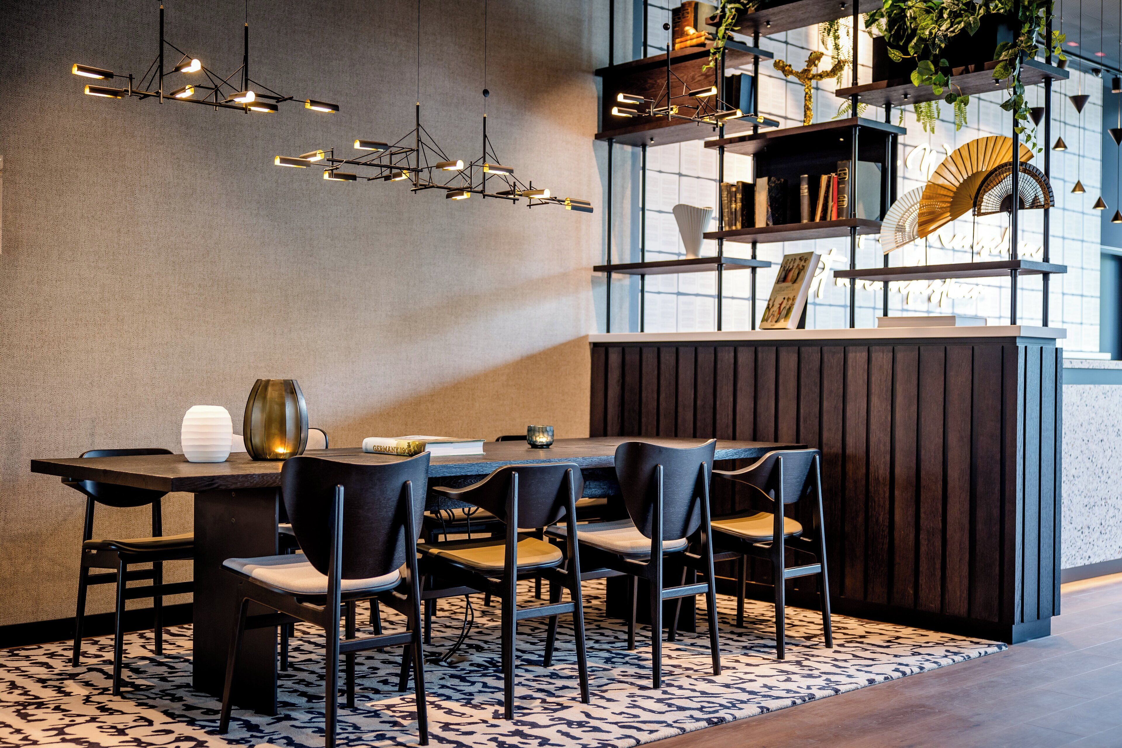 Un comedor moderno con una mesa de madera, sillas negras e iluminación colgante.