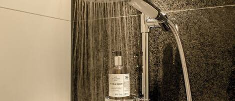 Un cabezal de ducha con una botella de producto para cabello y cuerpo colgando debajo.