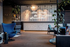 Un área de recepción moderna con un letrero de neón, asientos y una planta.