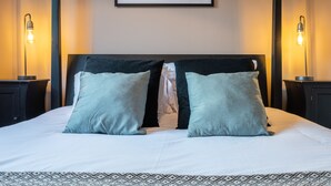 Een net opgemaakt bed met twee kussens, een hoofdbord en twee bedlampjes.