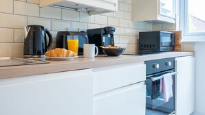 Een moderne keuken met een koffiezetapparaat, magnetron, broodrooster en een schaal fruit.