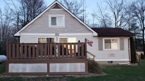 A two-story house with a wooden deck in front, a chimney, and a small attached garage.