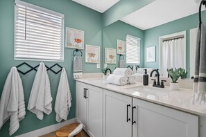 A bathroom with teal walls, white cabinets, a sink with a black faucet, and a potted plant. - 2 Mi. To Coachella Festival - Pool, Spa, Gameroom (Coachella)