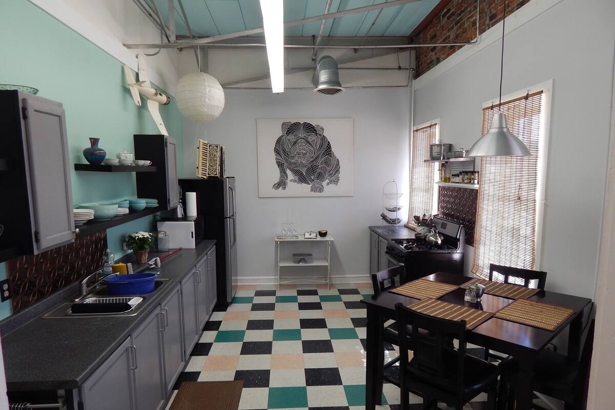 A compact kitchen with a checkered floor, a dining table with chairs, and a hanging light fixture.