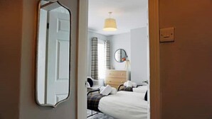 A bedroom with a bed, a dresser, a mirror, and a lamp. - Stylish 3 Bedroom Victorian Villa with hot tub (Lincoln)