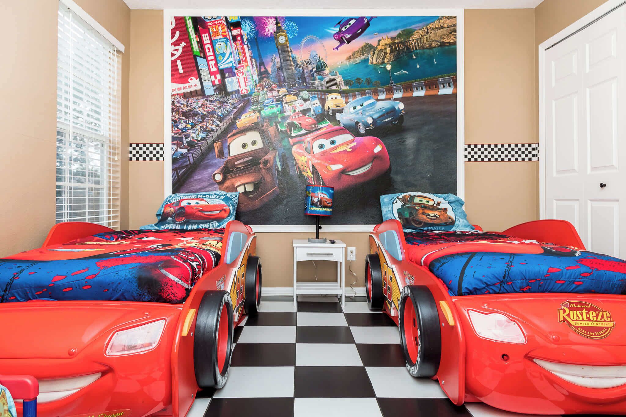 Quarto com duas camas, um mural grande na parede e piso xadrez.