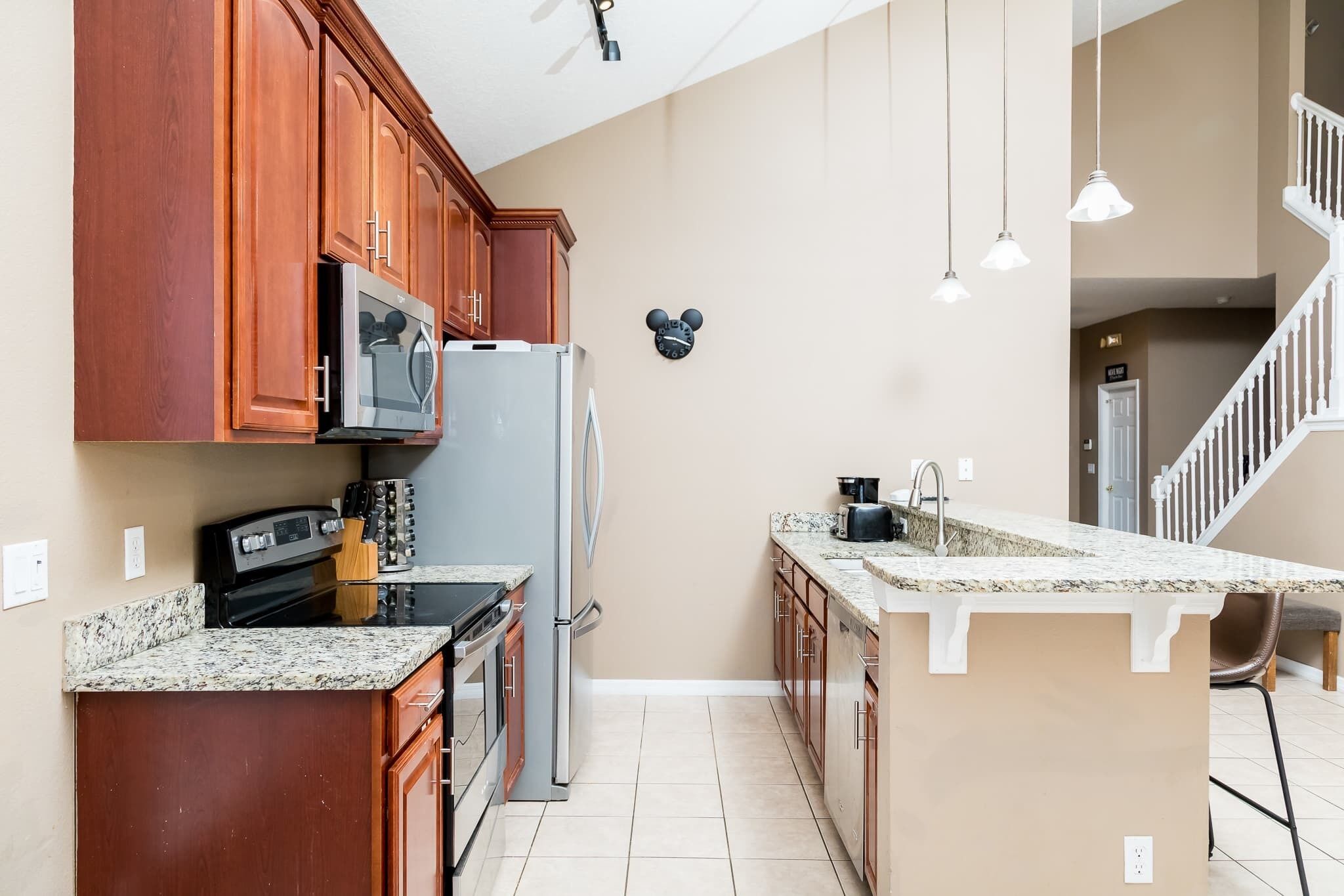 A kitchen with wooden cabinets, a microwave, a refrigerator, a stove, and a sink.