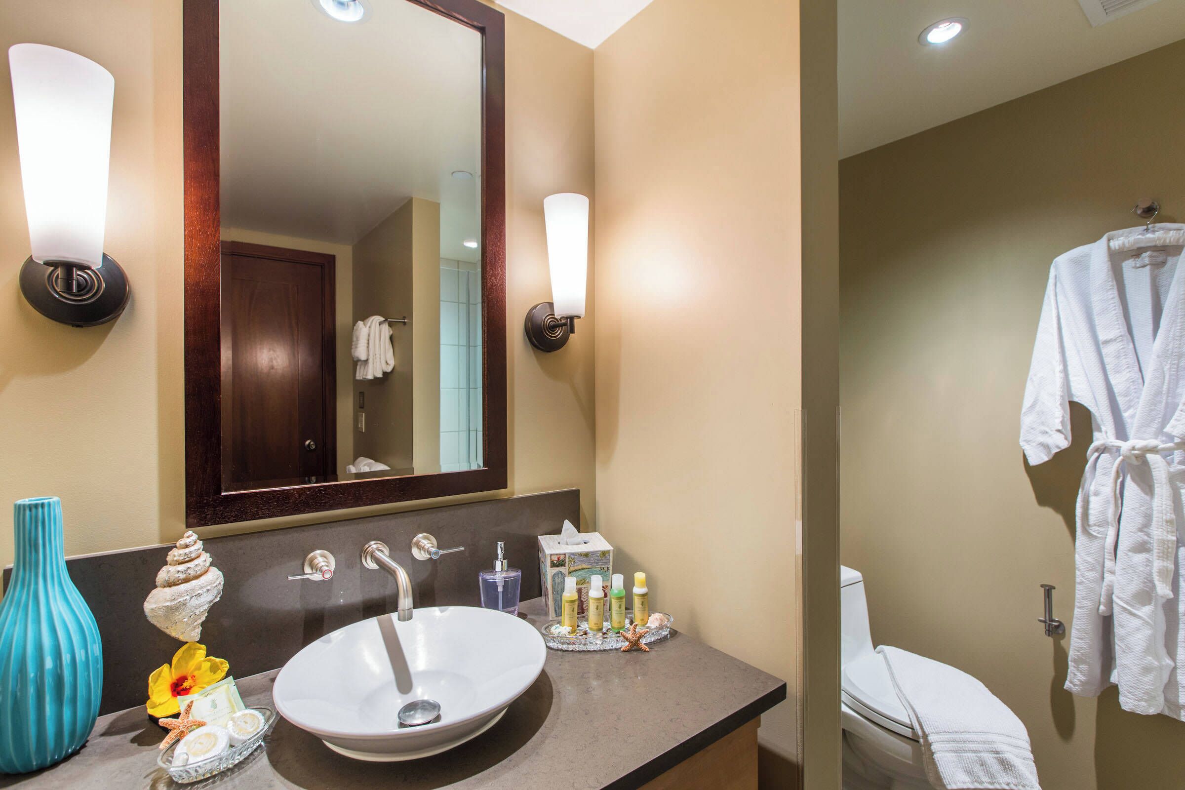 A bathroom with a large mirror, a sink, and a towel rack.