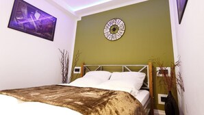 A bedroom with a bed, a wall clock, a framed picture, and a vase with plants. - Apartment top location in Tiergarten, directly on the Spree, near Bellevue S-Bahn. (Berlin)