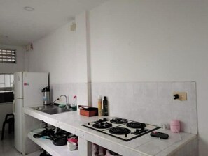 A compact kitchen with a gas stove, a refrigerator, and a sink. - Cozy, comfortable and central apartment (Pereira)