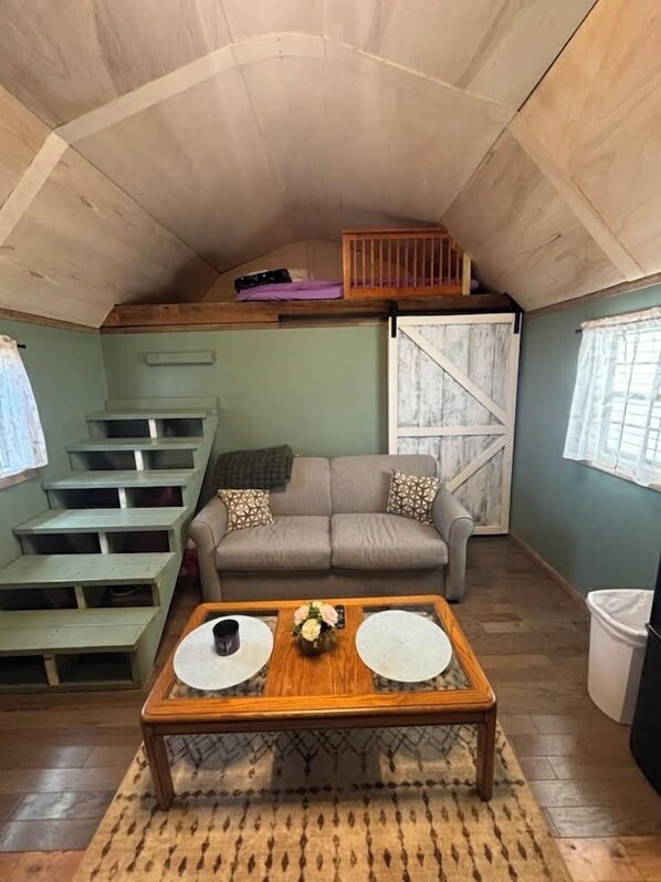 Un dormitorio tipo loft acogedor con sofá, una mesa de centro y una escalera.