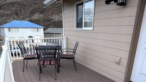 Een terras met tafel en stoelen, een witte balustrade en een gebouw met raam en lantaarn.