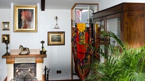 A room with a fireplace, framed pictures on the wall, a mirror, and a wooden cabinet. - Romantic attic with breathtaking views in the old town centre. (Napoli)