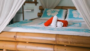 A bed with a canopy, a wooden headboard, and a floral-patterned bedspread. - Lagon - Charming Creole studio 2 steps from the sea (Sainte-Anne)