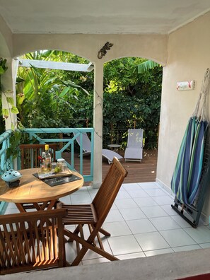 Un patio cubierto con una mesa y sillas de madera, una hamaca y vistas de vegetación exuberante.