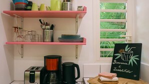 A kitchen with a toaster, coffee maker, and shelves with kitchenware. - Zikak - Charming Creole cottage 2 steps from the sea (Sainte-Anne)