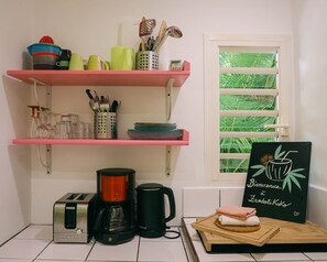 A kitchen with a toaster, coffee maker, and shelves with kitchenware.