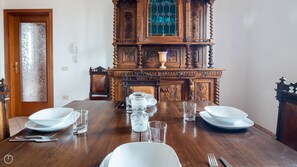 Taula de dinar coberta amb plats blancs, gots i cubertries, acompanyada d'ornats mobles de fusta amb detalls tallats.