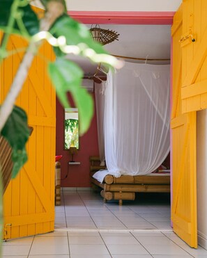 Una habitación con una cama, una cesta colgante y una ventana.