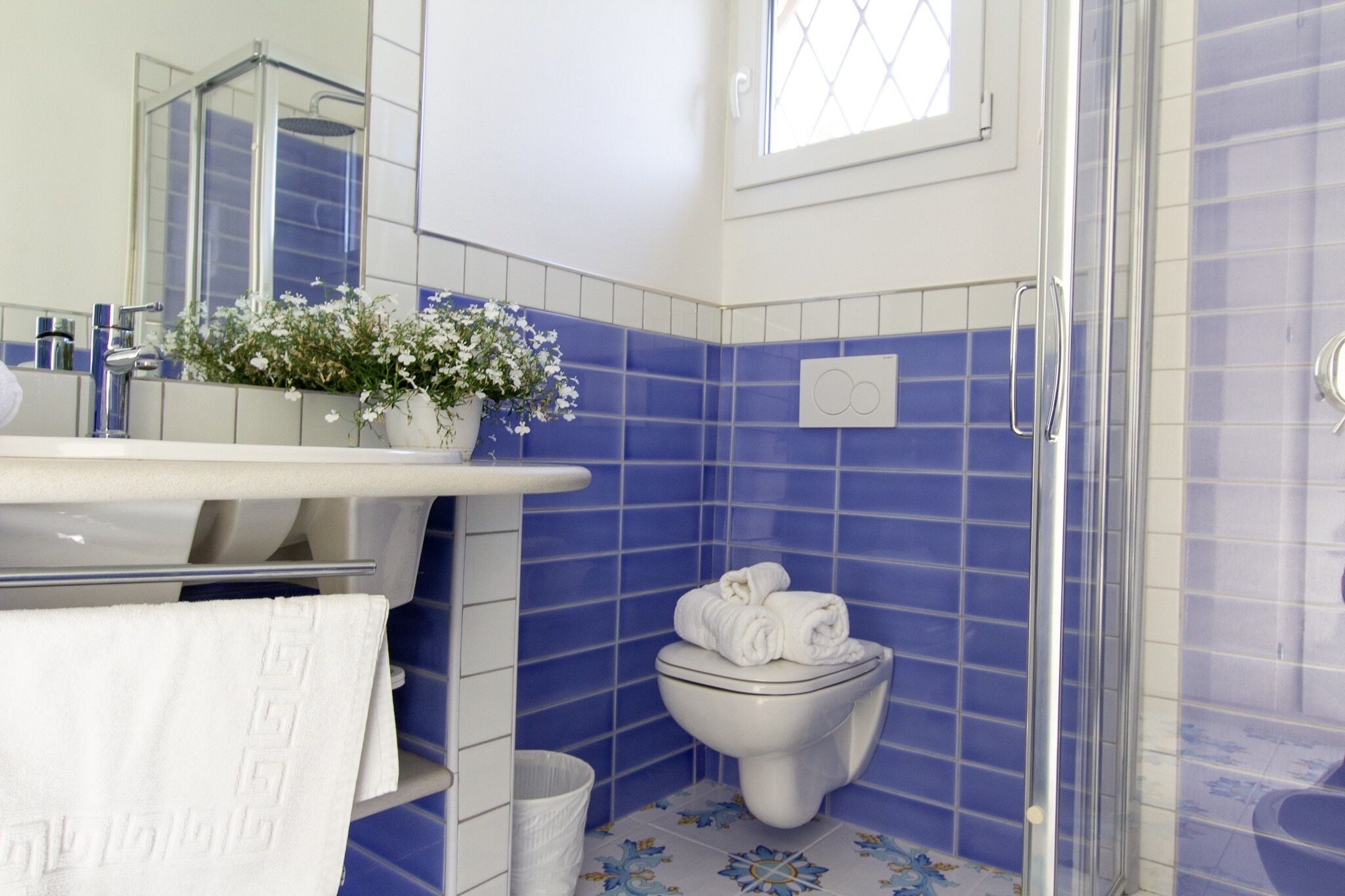 Une salle de bain avec un lavabo blanc, un miroir, des toilettes et un espace douche.