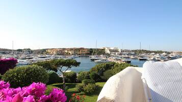 A marina with numerous boats docked, surrounded by greenery and buildings in the background.