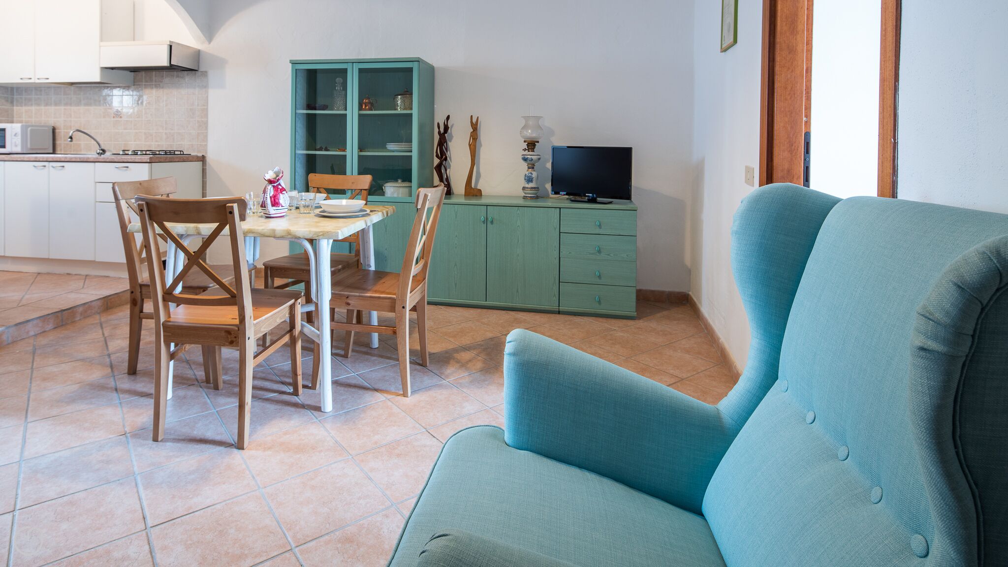 A compact living space with a dining area, a sofa, a TV, and a green cabinet.