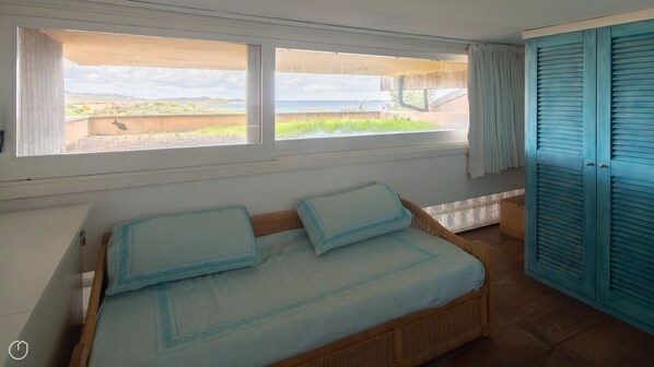A bedroom with a bed, a window with a view of the outdoors, and a blue wardrobe.