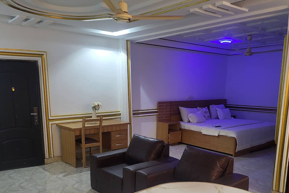 A bedroom with a bed, a desk, and a chair.