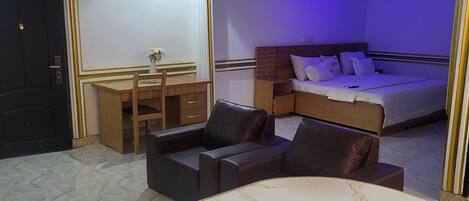 A bedroom with a bed, a desk, and a chair.