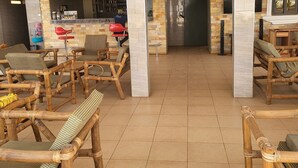 Un espace intérieur spacieux, doté de chaises en bambou et d’un bar avec des bouteilles et des verres.