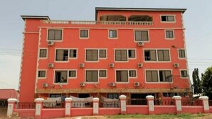 Un immeuble à plusieurs étages, doté d’une façade rouge, de nombreuses fenêtres et de climatiseurs.