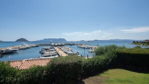 A marina with boats docked, a clear sky, and a distant mountain. - Villa Acqua Marina - Four Bedroom Villa, Sleeps 8 (Golfo Aranci)