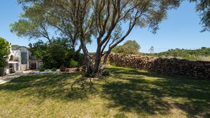 A stone wall, a large tree, and a building with a sloped roof. - Mediterranea - One Bedroom Apartment, Sleeps 4 (Loiri)