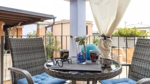 A balcony with wicker chairs, a round table, and a potted plant. - Nido Blu Tortolì | Terrace, Hammock & Park (Tortoli)