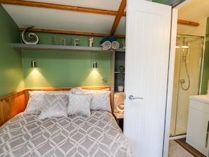Ein Schlafzimmer mit einem Bett, einem Regal mit Dekoration, einer Wandleuchte und einem Duschbereich.